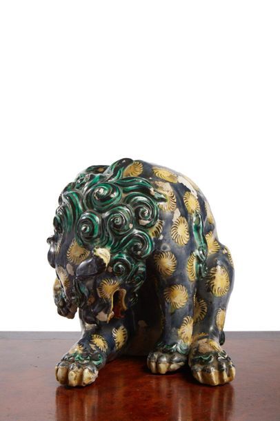 Statuette of sitting shishi licking his hind...