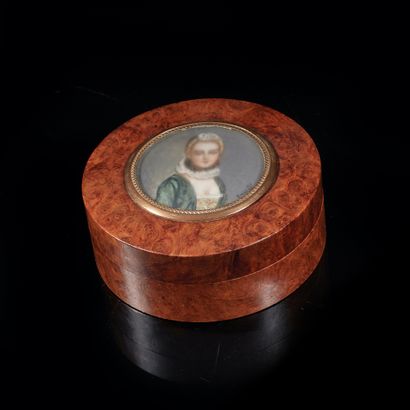 A circular burlwood box with a lid decorated...