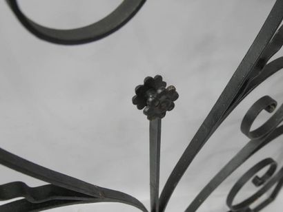 Grille en fer forgé à décor de volutes entourant...