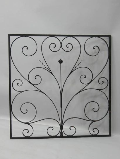 Grille en fer forgé à décor de volutes entourant...