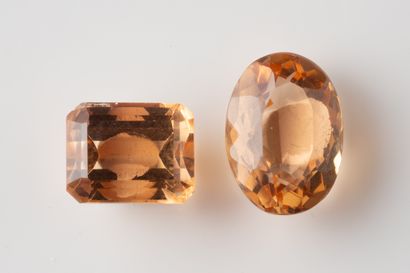 2 salmon-colored topazes on paper. One oval-cut...