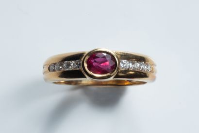 Band ring centered on an oval faceted ruby...
