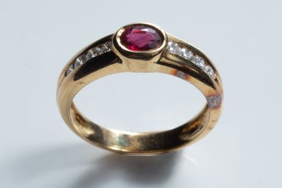 Band ring centered on an oval faceted ruby...