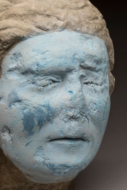 Carved limestone head; strands of hair falling...