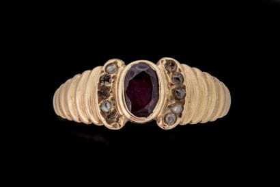 A band ring set with an oval ruby flanked...