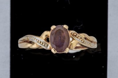 Worn ring set with a faceted oval amethyst...
