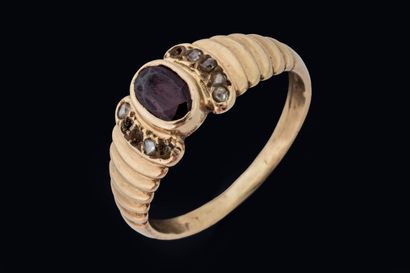 A band ring set with an oval ruby flanked...