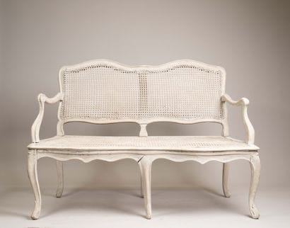 A cane-seated sofa with molded wood and a...