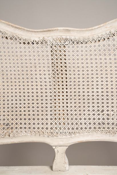A cane-seated sofa with molded wood and a...