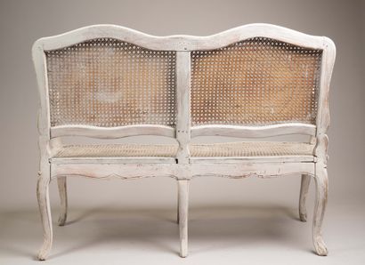 A cane-seated sofa with molded wood and a...