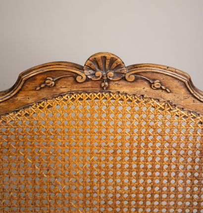 A cane-seated armchair with a flat back made...