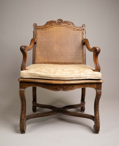 A cane-seated armchair with a flat back made...