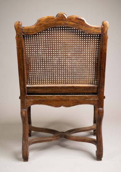 A cane-seated armchair with a flat back made...