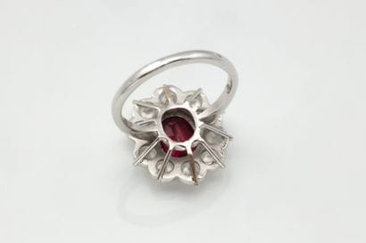 Daisy ring centered on an oval ruby in a...
