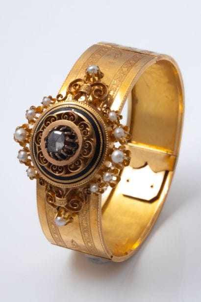 Clasp-style bangle featuring a central rosette...