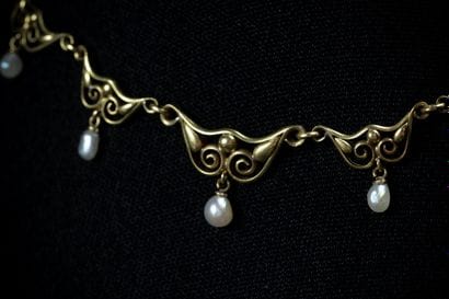 Draped necklace adorned with white pearl...