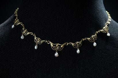 Draped necklace adorned with white pearl...