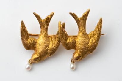 Brooch featuring two flying swallows in yellow...