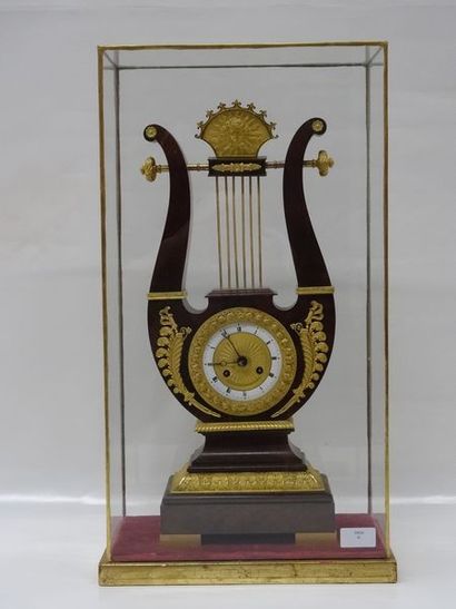 Dans une cage en verre, pendule lyre en acajou,...