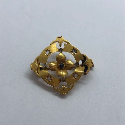 Broche en or 18K à décor ajouré et centrée...