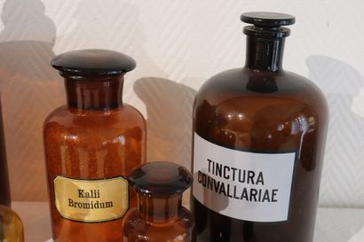 Suite de huit pots à pharmacie en verre ambre....