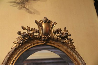 Miroir ovale en bois sculpté et doré, surmonté...