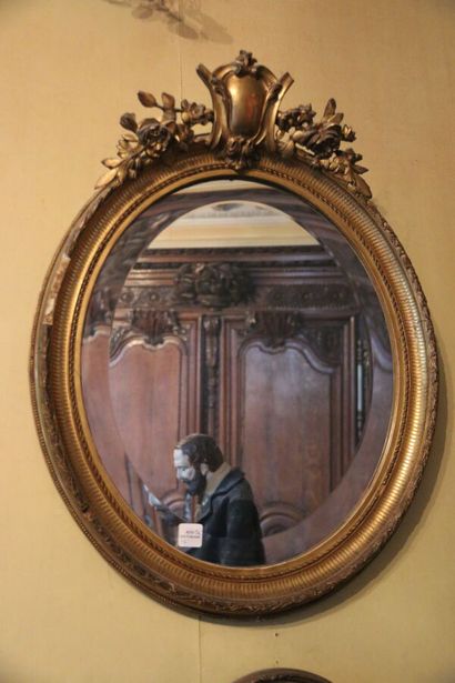 Miroir ovale en bois sculpté et doré, surmonté...