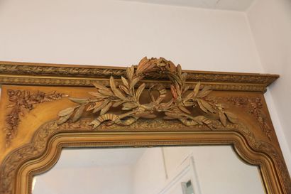 Grand miroir en bois et stuc doré surmonté...