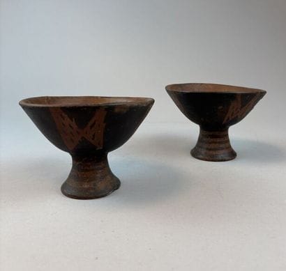 Two terracotta cups on a pedestal with geometric...