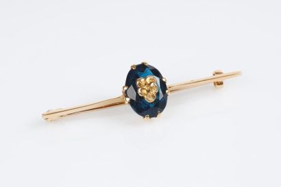 Broche en or centrée d'une pierre bleue ovale...