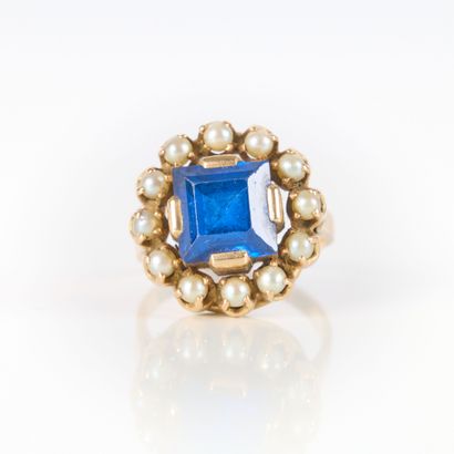 Gold ring set with a blue stone surrounded...