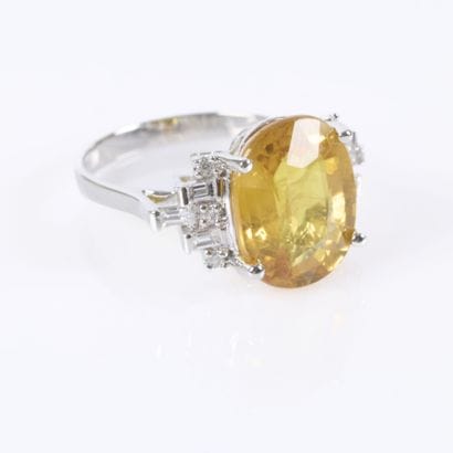 White gold ring set with an oval-cut yellow...