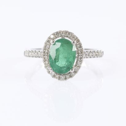 White gold ring set with an oval-cut emerald...
