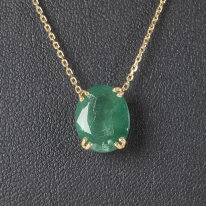 Gold necklace featuring an oval-cut emerald...