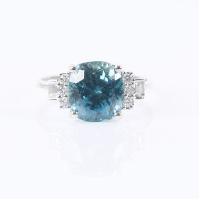 White gold ring set with a cushion-cut blue...