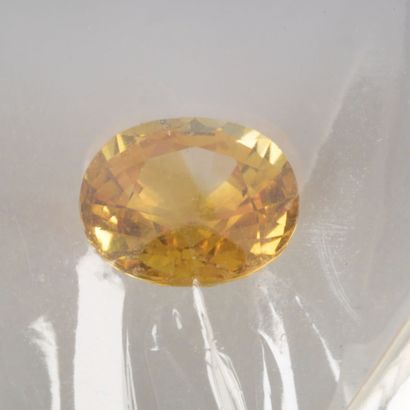 Saphir ovale jaune orange sous scellé, accompagné...