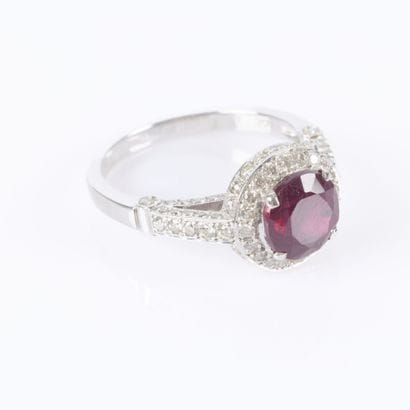 White gold ring set with a round ruby surrounded...