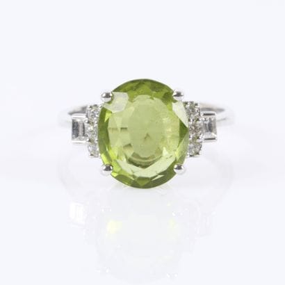 White gold ring set with an oval-cut peridot...