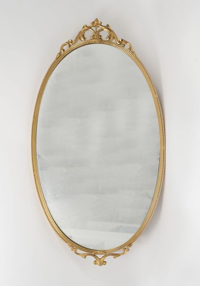 A gilt brass framed oval mirror decorated...