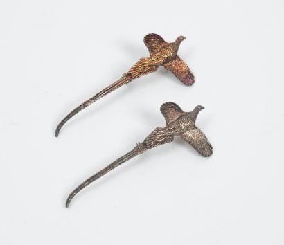 Two small patinated metal jewels in the shape...