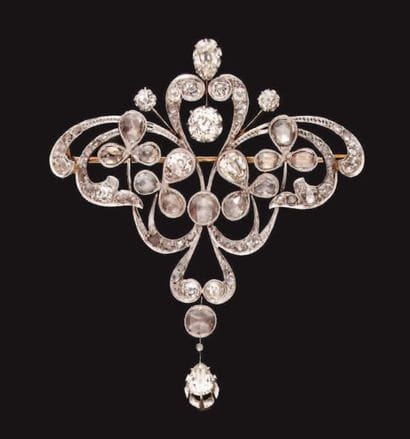 Broche volute à décor de fleurs, en or ajouré,...