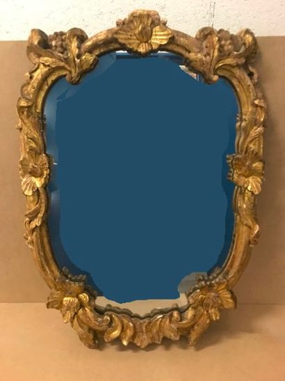 Miroir en forme d'écusson chantourné au cadre...