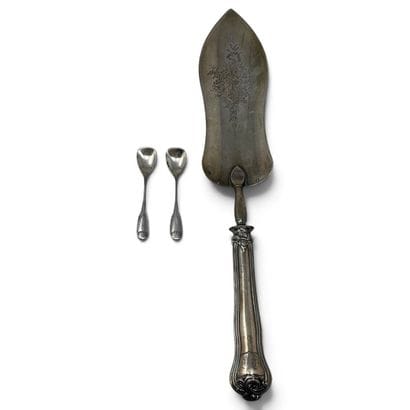 A silver serving scoop decorated with a bouquet,...