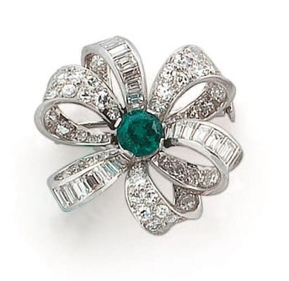 Broche fleur en or gris centrée d'une émeraude...