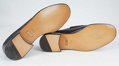 GUCCI 
Black leather penny loafers adorned...