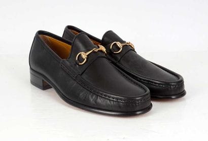 GUCCI 
Black leather penny loafers adorned...