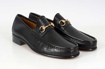 GUCCI 
Black leather penny loafers adorned...