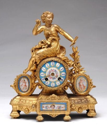 HORLOGE à patine dorée et médaillon en porcelaine...