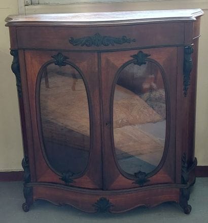 A display cabinet in natural wood, with curved...