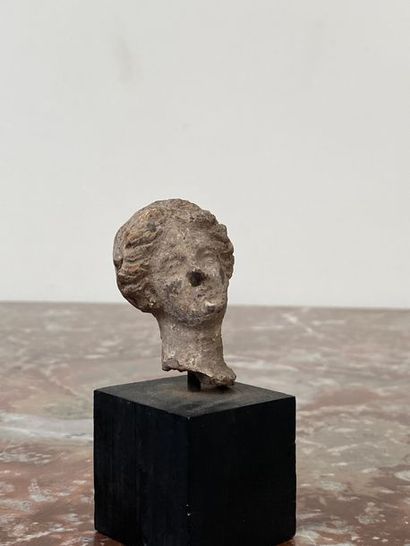 Terracotta female head, hair styled in wavy...